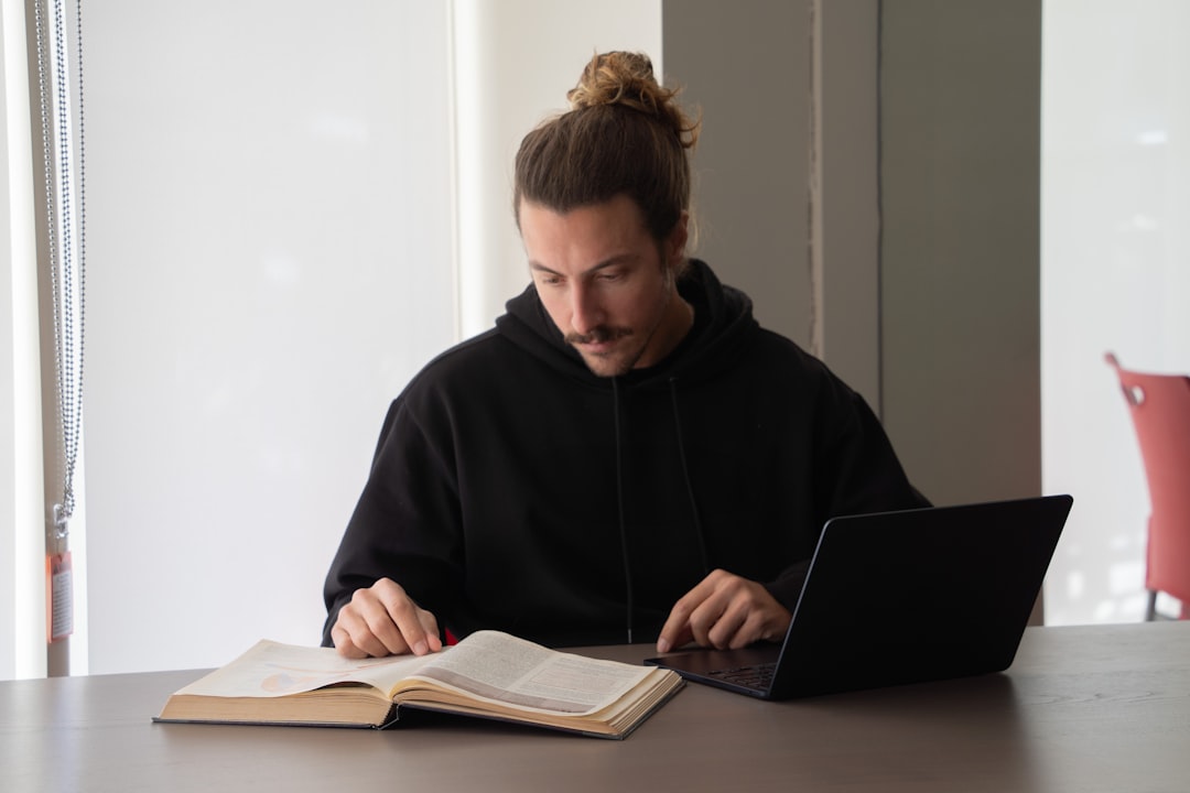 Estudiante usando un ordenador portátil y un libro para estudiar Secundaria online
